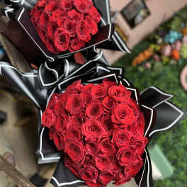 Two bouquets of red roses wrapped in black paper with white trim