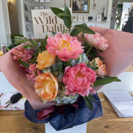 Bouquet of pink, peach, and yellow flowers wrapped in pink paper
