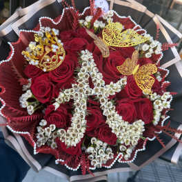 Hand-tied bouquet of red roses with white flowers shaped into a letter and gold crown and butterfly accents