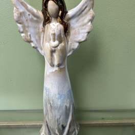 Ceramic angel figurine with outstretched wings on a green wall