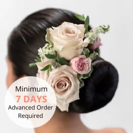 Blush and pink roses arranged as a floral hairpiece on a sleek dark hair bun