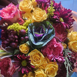Hand-tied bouquet of yellow roses, pink blooms, purple mums, and ornamental cabbage in plaid wrap