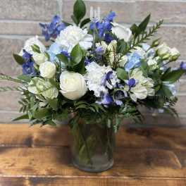White and blue mixed flower arrangement in a clear glass vase.