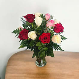 Bouquet of red, pink, and white roses in a clear glass vase