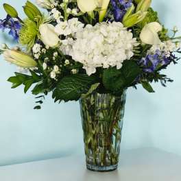 White and blue floral arrangement in a clear glass vase