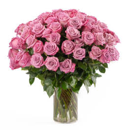 Large bouquet of pink roses arranged tightly in a clear glass vase