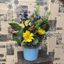 Mixed bouquet in a blue pot with yellow daisies and purple blooms