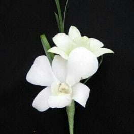White dendrobium orchid boutonniere with slim grass accents on a black background