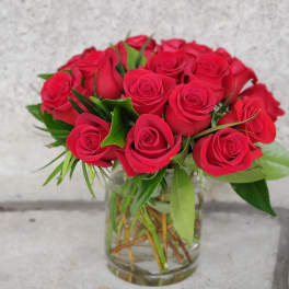 Arrangement of red roses tightly clustered in a clear glass vase