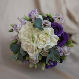 Round bouquet of white roses with purple and lavender lisianthus on a neutral background