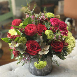 Round arrangement of red roses with green hydrangea in a gray marbled vase