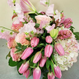 Pink tulips, roses, lilies, hydrangea, and other pastel flowers in a lush mixed arrangement