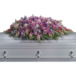 Lavender and pink casket spray with roses, snapdragons, and mixed flowers on a silver casket