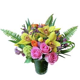 Colorful arrangement of yellow orchids and pink roses in a clear glass vase