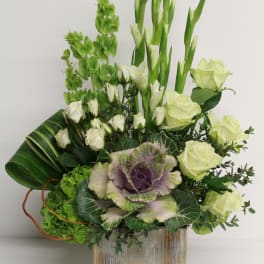 Asymmetrical arrangement of white roses and green blooms with ornamental cabbage in a rustic wood box.