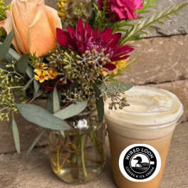 Bouquet of peach and magenta flowers in a glass vase beside a lidded iced drink