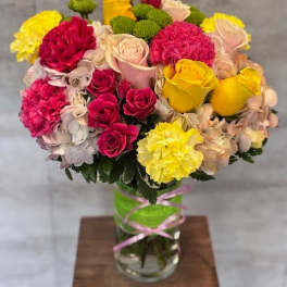 Mixed bouquet of roses, carnations, and hydrangeas in a glass vase