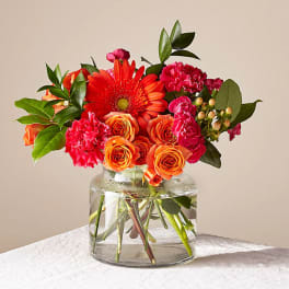 Orange and pink flowers arranged in a clear glass vase