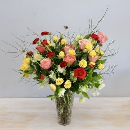 Mixed roses and small white flowers in a clear glass vase