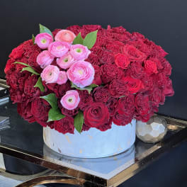 Large red and pink rose arrangement in a round white box