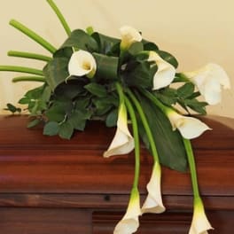White calla lilies arranged on a wooden casket
