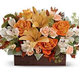 Orange roses and lilies in a rectangular wooden container