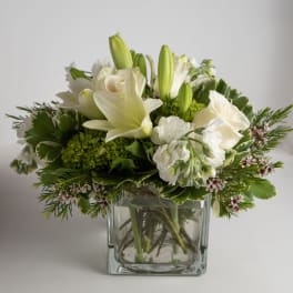White lilies and roses arranged in a clear glass vase