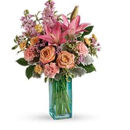 Pink and peach floral arrangement in a blue glass vase