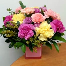 Colorful bouquet of carnations in a pink square vase