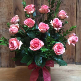 Pink roses arranged in a glass vase with a pink ribbon