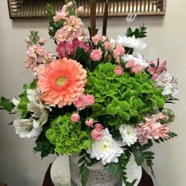Mixed pink, white, and green floral arrangement in a speckled container