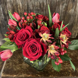 Red roses and pink tulips arranged in a glass vase