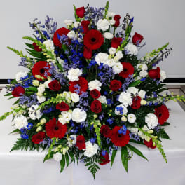 Large red, white, and blue floral spray with roses and gerbera daisies