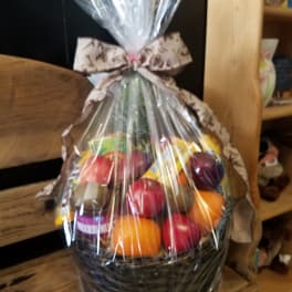 Cellophane-wrapped fruit and snack gift basket tied with a patterned bow.