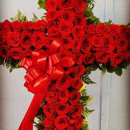 Cross-shaped arrangement of red roses with a red ribbon bow