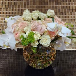White orchids and pale roses arranged in a glass vase