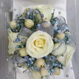 White rose bouquet with blue accents and silver ribbon in a clear box