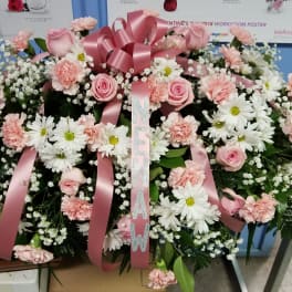 Pink and white funeral spray with roses, carnations, and daisies