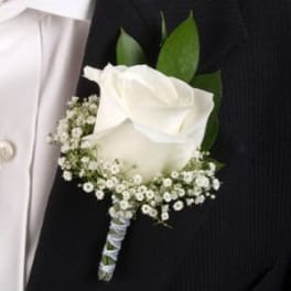 White rose boutonniere with tiny white filler flowers on a black suit lapel