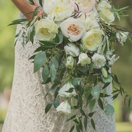 Cascading bridal bouquet of white and cream roses with trailing foliage