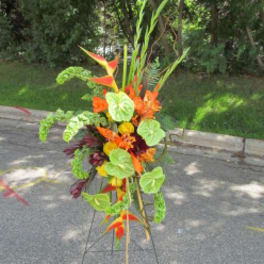 Tall tropical flower arrangement with orange blooms and green leaves on a stand
