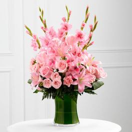 Pink lilies and roses arranged in a green glass vase