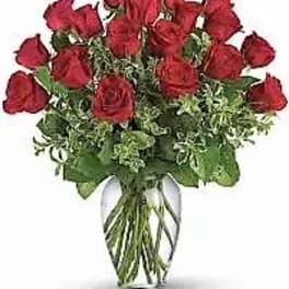 Arrangement of red roses with foliage in a clear glass vase