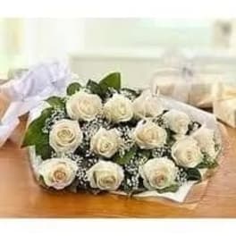 Wrapped bouquet of white roses with baby's breath lying on a wooden surface