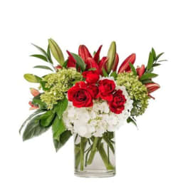 Bouquet of red roses, white hydrangeas, and lilies in a clear glass vase