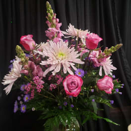 Pink roses and pale daisies arranged in a glass vase