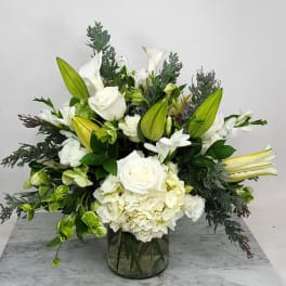 White floral arrangement with lilies, roses, and hydrangea in a glass vase