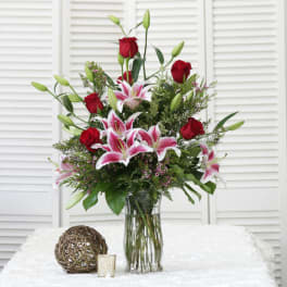 Red roses and pink lilies arranged in a clear glass vase