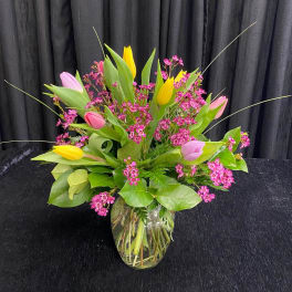 Bouquet of pink and yellow tulips in a clear glass vase