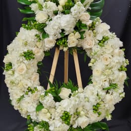 White floral funeral wreath on a wooden easel with roses and hydrangeas